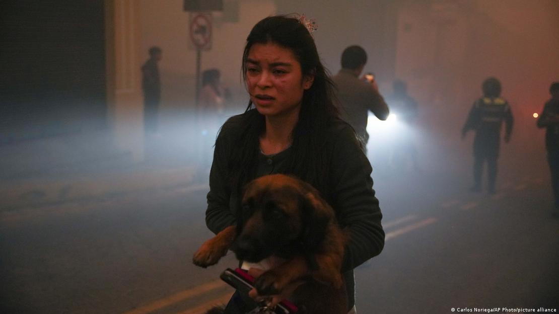 Una residente del barrio Guapulo lleva a un perro en medio del espeso humo de los incendios en una zona boscosa cercana en Quito.