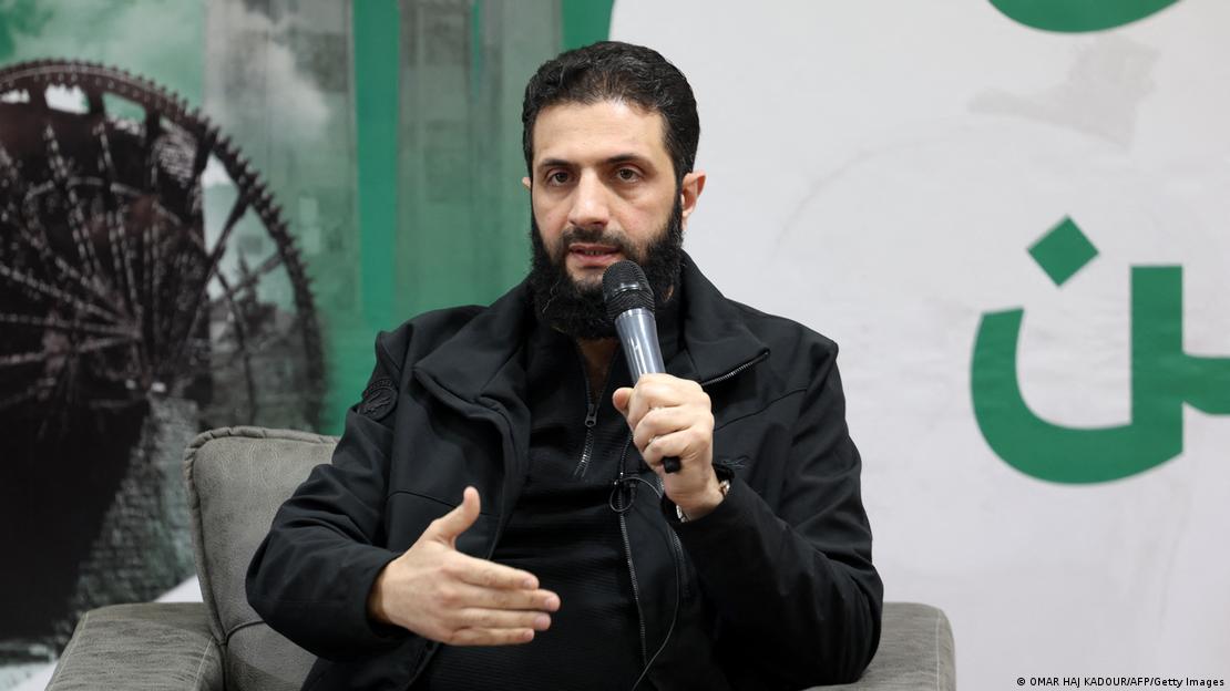 Abu Mohamed al Julani habla con micrófono sentado en sillón