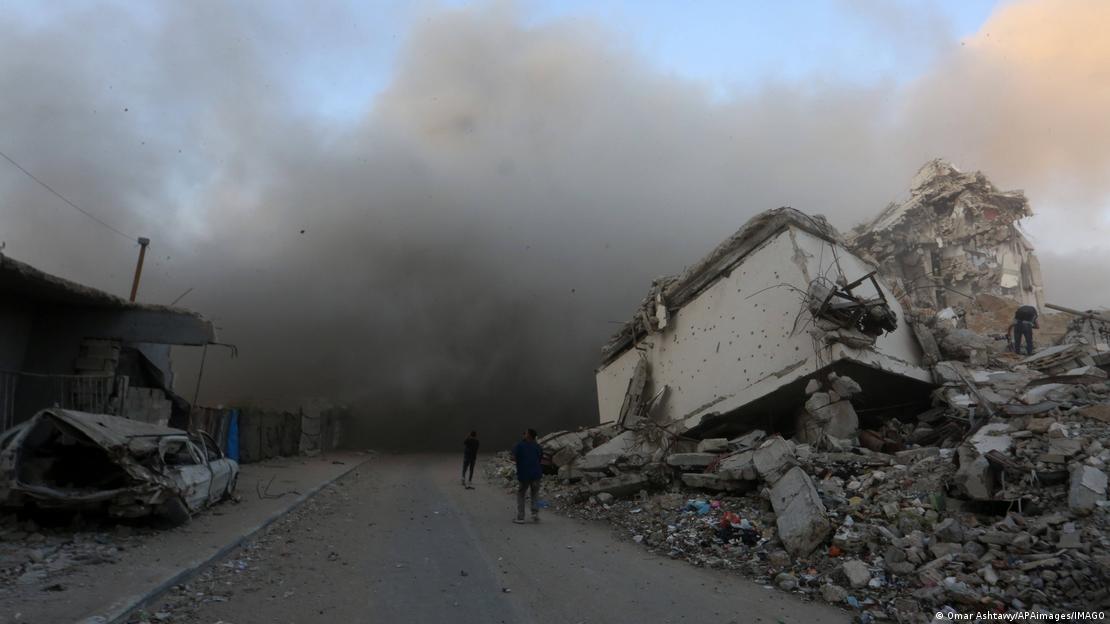 Destrucción en medio de ataques israelíes en Ciudad de Gaza. Al frente ruina, al fondo, humo negro y gris.