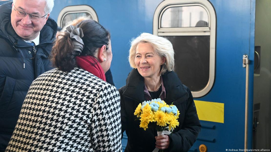 La presidenta de la Comisión Europea, recibida con un ramo de flores con los colores de la bandera ucraniana tras bajarse del tren, con el ministro Sibiga sonriente a su lado.