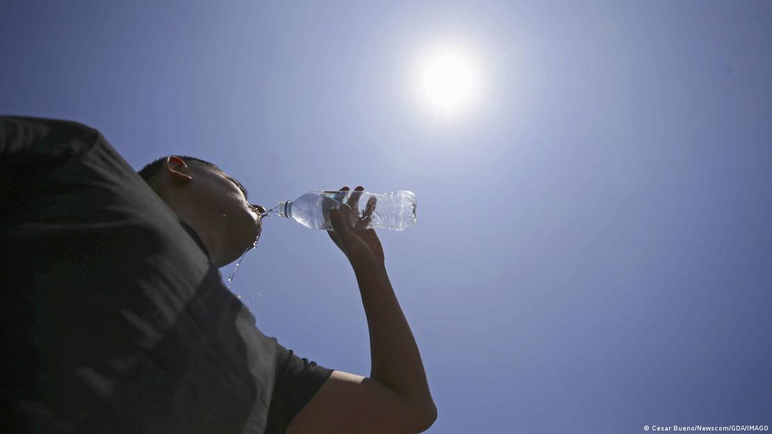 Un hombre toma agua de una botella en Lima, Perú, bajo un sol ardiente, en la ola de calor extremo. (2024).