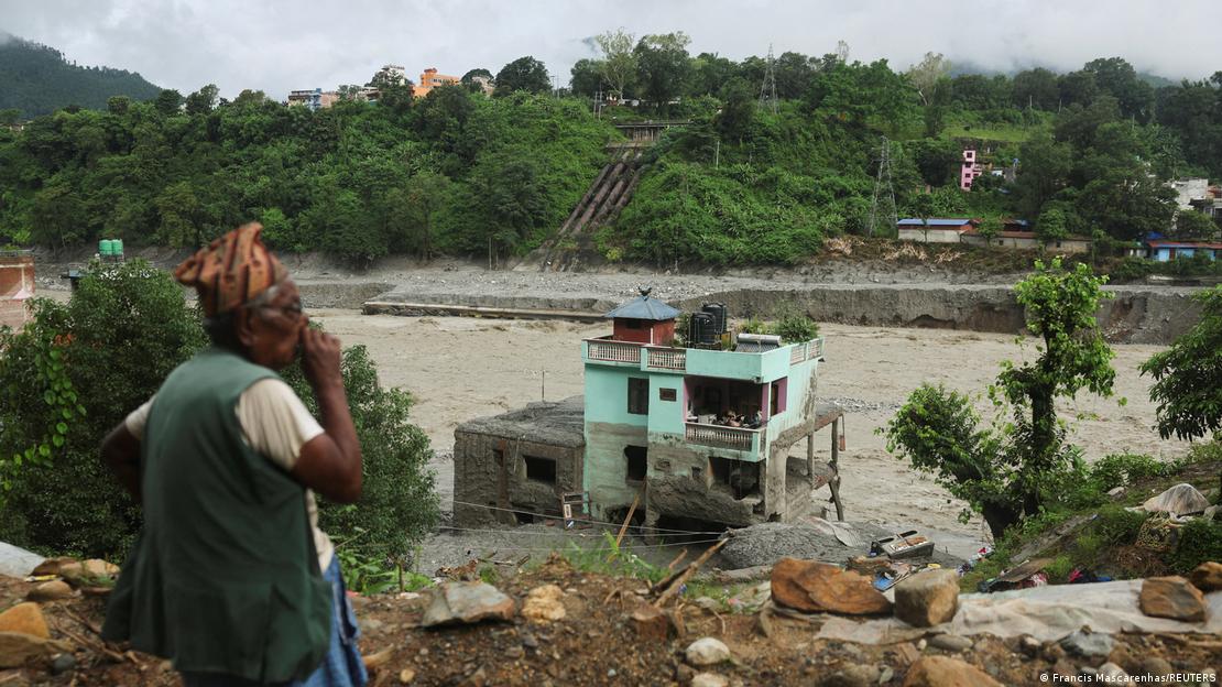 Un hombre observa la "casa verde milagrosa" en medio de los escombros tras haber sobrevivido a inundaciones repentinas en Trishuli, Nepal.
