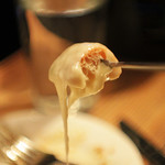 Piece of bread dipped in the Raclette fondue