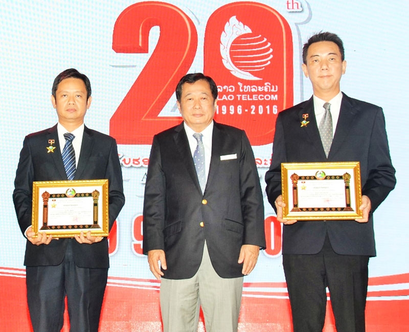 20 ปี แอลทีซี : ดร.ทันสะไหม กมมะสิด รมว.กระทรวงไปรษณีย์ โทรคมนาคม และการสื่อสาร สปป.ลาว มอบเหรียญตราแรงงาน ให้แก่ ปิยะวัฒน์ จริยเศรษฐพงศ์ ผจก.ทั่วไปอาวุโส และ ปวริศร์ เอี่ยมอ่ำ ผจก.ฝ่ายบัญชีและการเงิน บจก.ลาว เทเลคอมมิวนิเคชั่นส์ (แอลทีซี) ในเครือ บมจ.ไทยคม ผู้มีผลงานคุณความดี