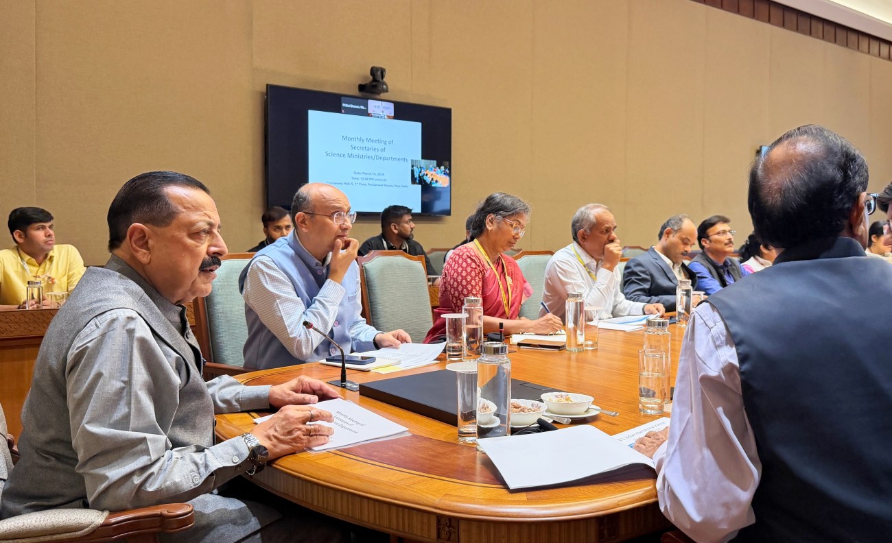 A group of officials attending a monthly meeting of science ministries, seated around a large table with notes and glasses of water in front of them.