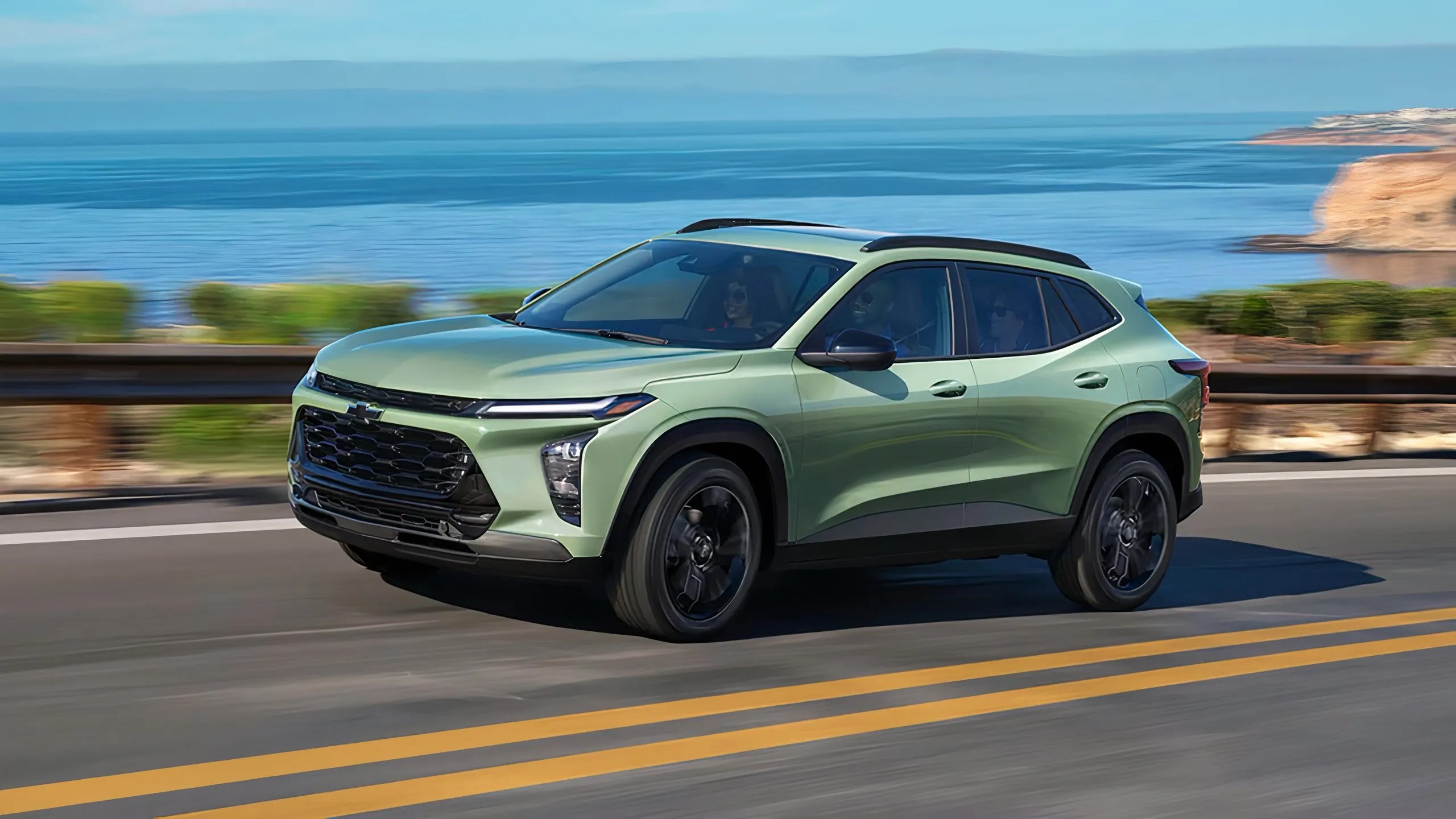 Une Chevy verte conduisant le long de l'eau. 