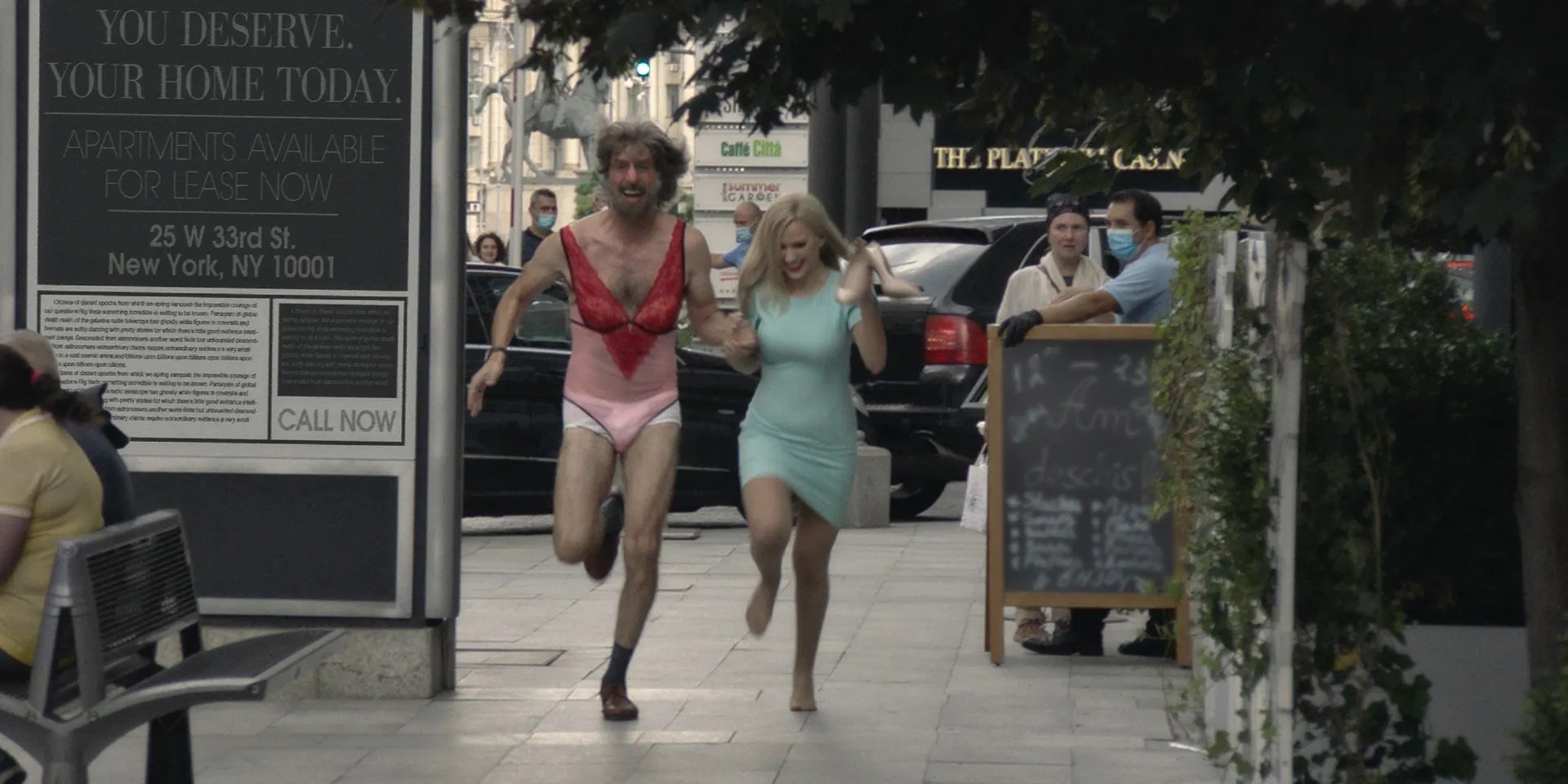 Sacha Baron Cohen y Maria Bakalova corriendo por la calle en Borat posterior Moviefilm