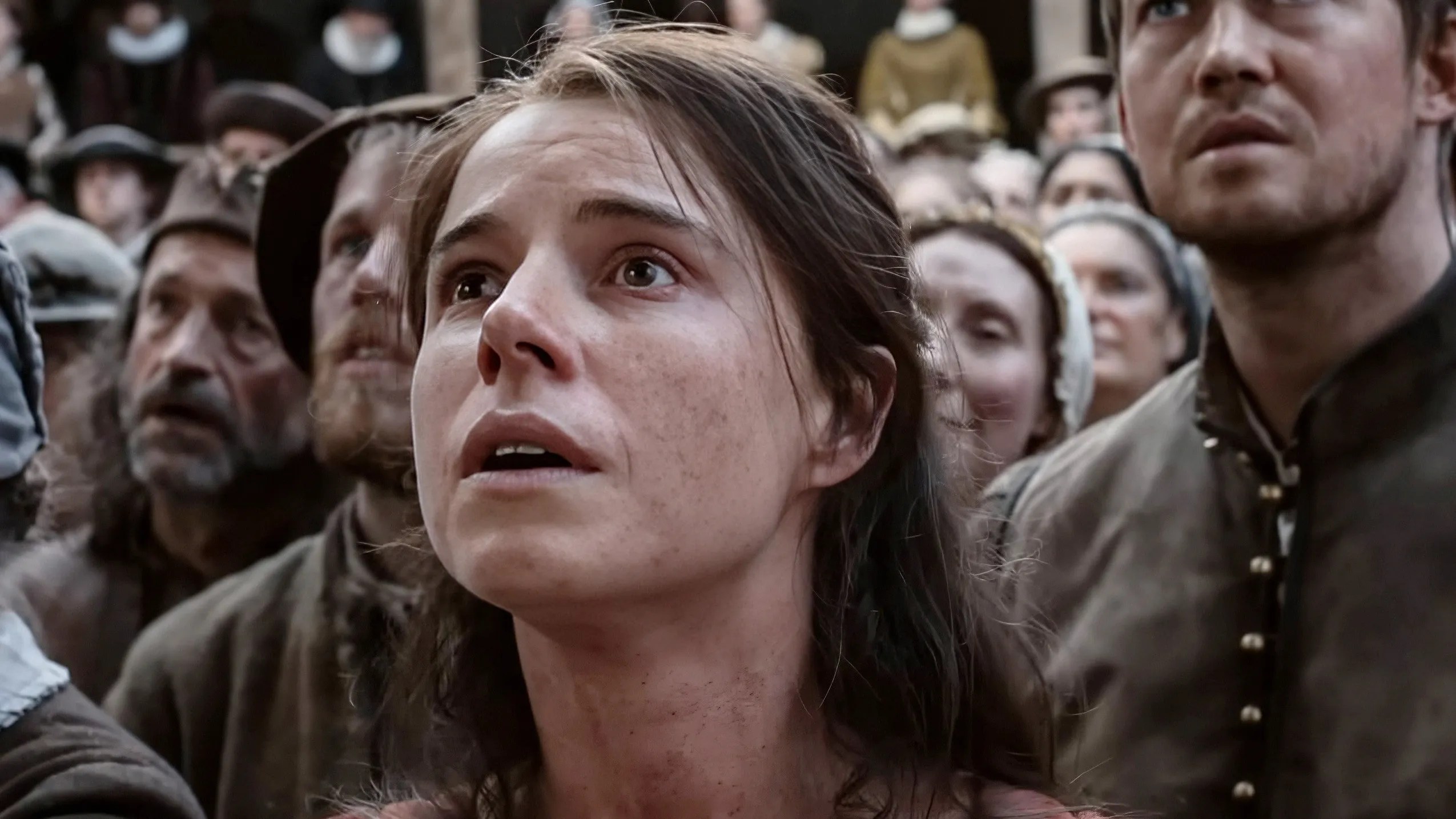 Jessie Buckley y una multitud mirando asombrada en Hamnet