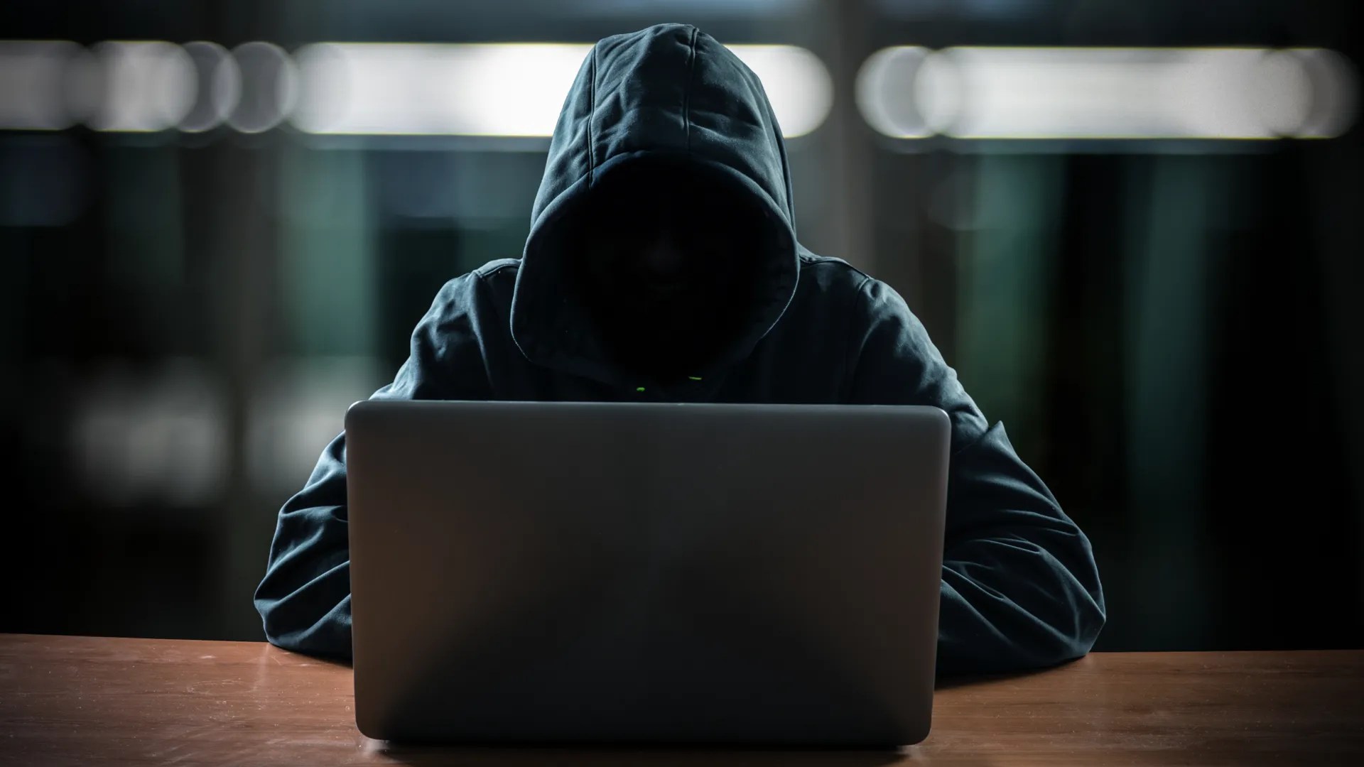 Hacker in front of his computer with a  dark face.