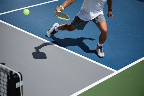 man lunging while hitting pickleball