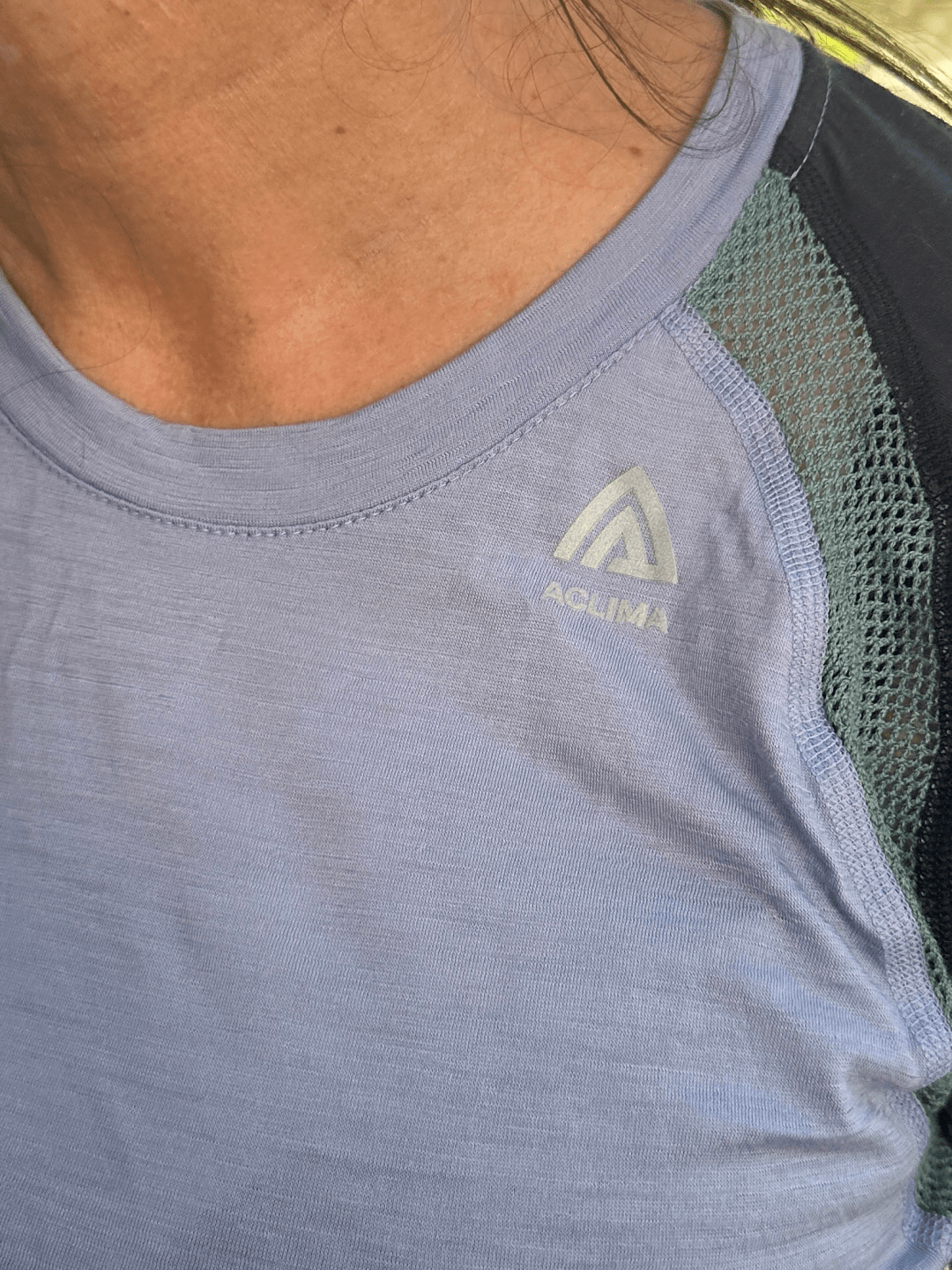 Detailaufnahme eines Aclima LightWool Shirts in Hellblau mit Logo auf der Brust und atmungsaktivem Netzeinsatz am Ärmeleinsatz.