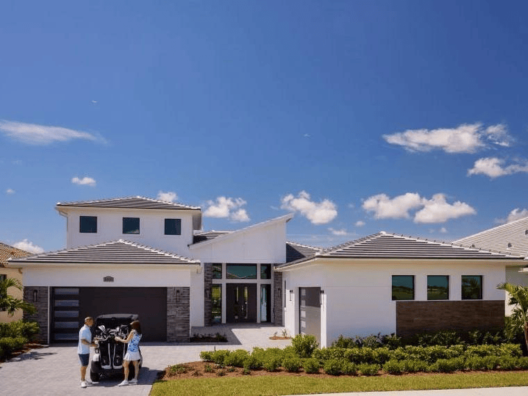 Single-family home with a golf cart in the driveway at Astor Creek Golf and Country Club in Port St. Lucie, Florida