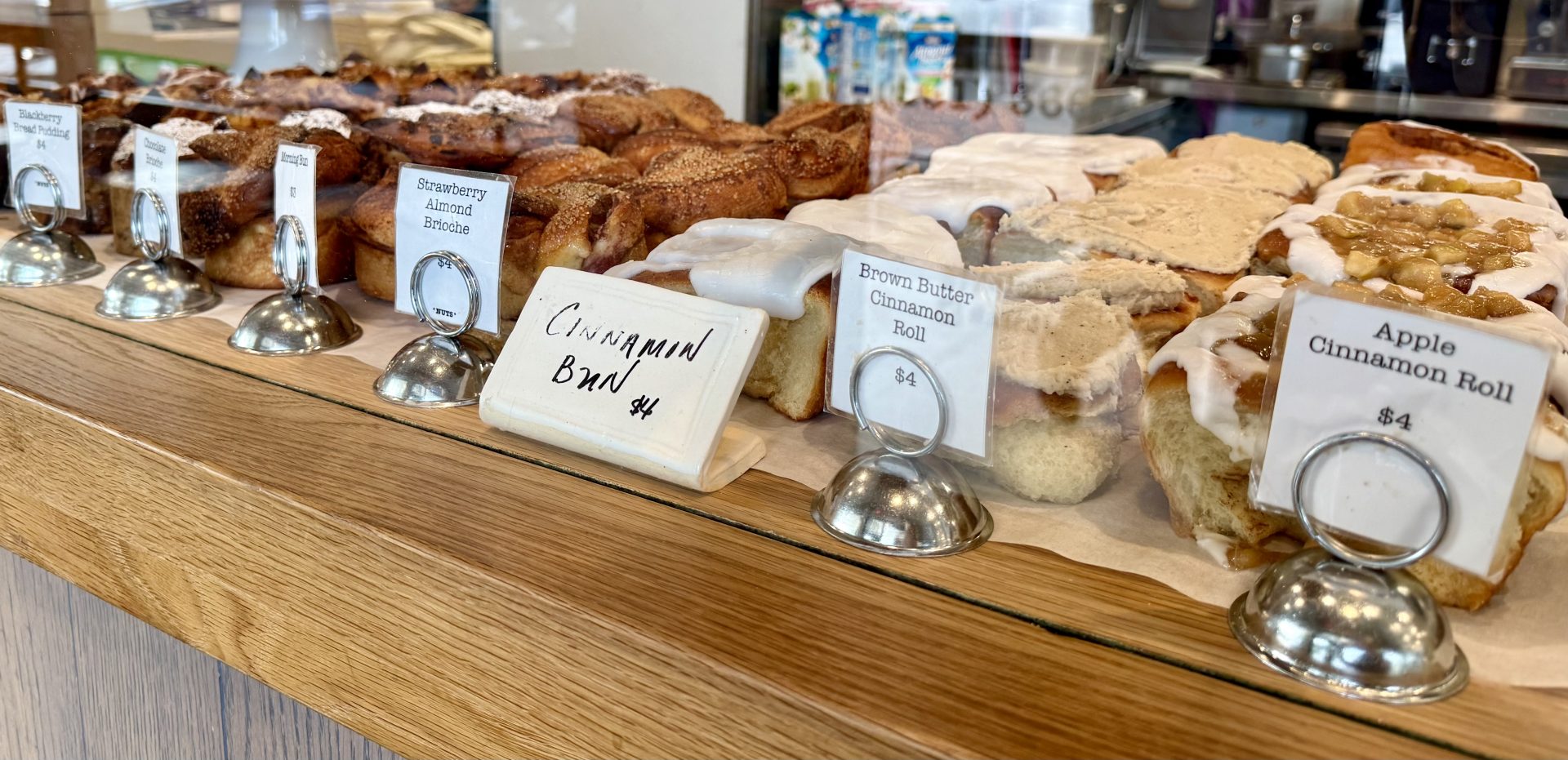 Pastries on a shelf with signs showing prices.