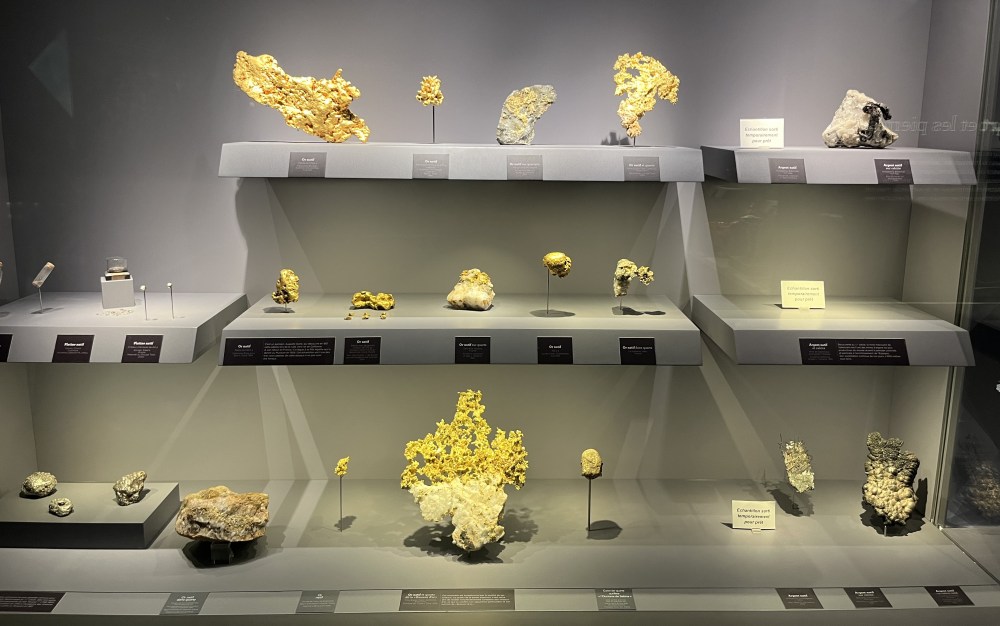 Display of precious metals including gold and other notable specimens, arranged in a modern exhibit within the Galerie de Géologie et de Minéralogie.