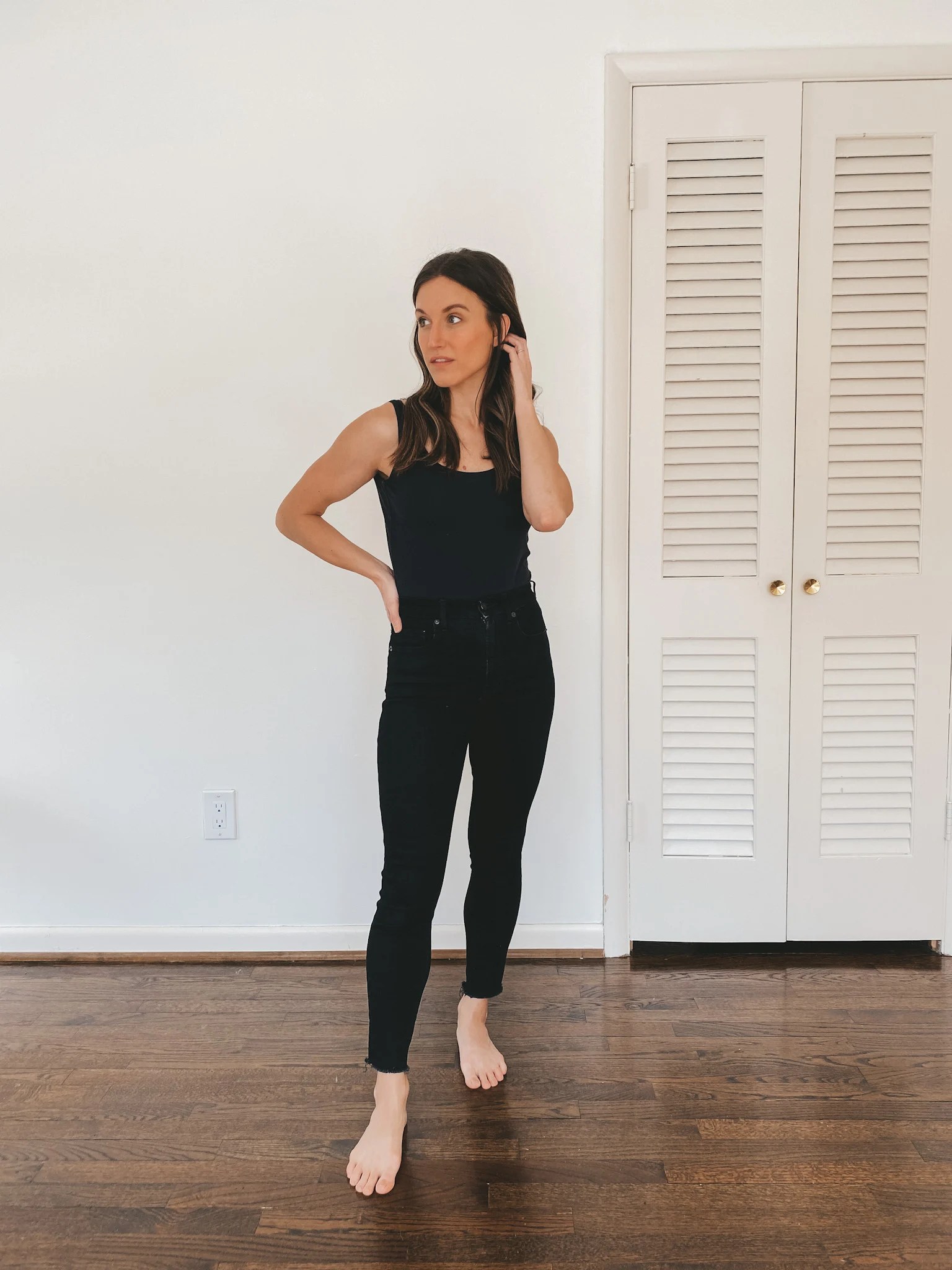 ashley wearing an Everlane black sleeveless bodysuit and black Authentic Stretch High Rise Skinny Jeans from Everlane