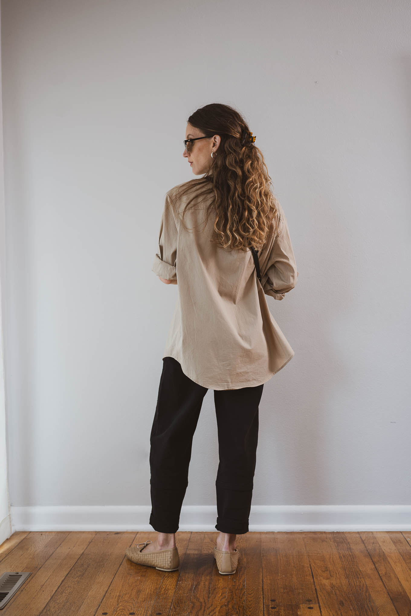 fall outfit idea with a tan button down, beige trench coat, black pants, and tan ballet flats