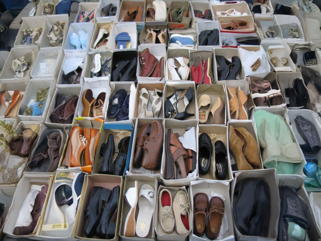 An overhead shot of many open shoeboxes arranged in a grid, each filled with a different pair of vintage-style shoes.