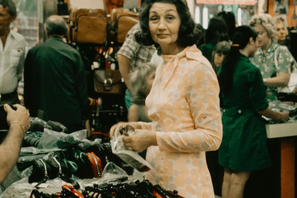 Woman in a patterned dress shops in a crowded retail space from Stockmark.it
