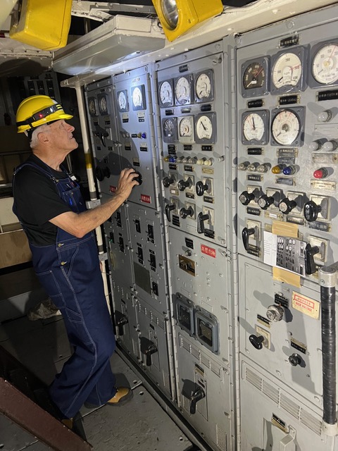 A person wearing a hardhat looks at abank of monitors