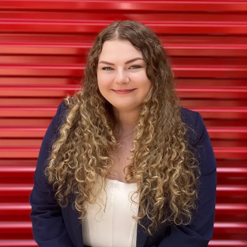 Brook Bland, Marketing Manager at Storage Defender, standing in front of a red storage unit door