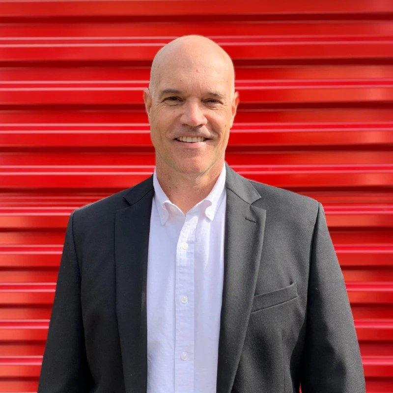 Chad Cable, Vice President of Operations at Storage Defender, standing in front of a red storage unit door