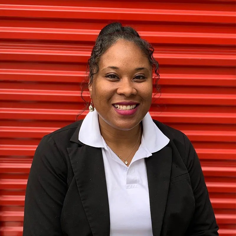 Shannel Armstrong, Chief of Staff at Storage Defender, standing in front of a red storage unit door