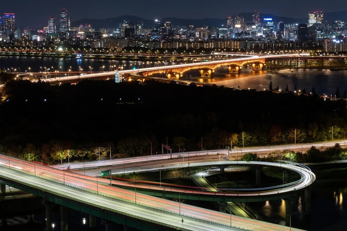 Night skyline and lit-up bridge, suggesting a city where the games could resurface