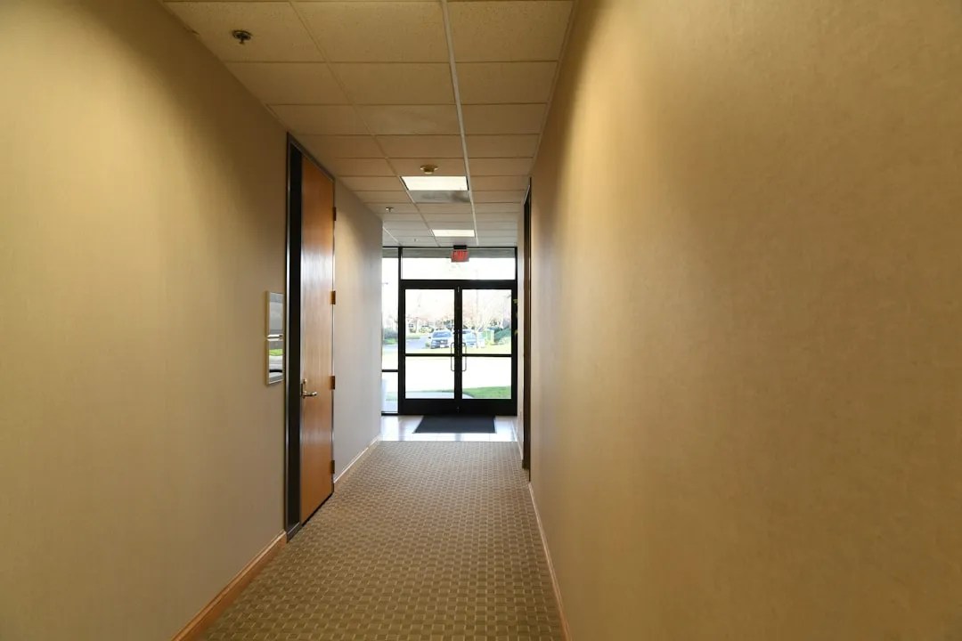 A stark white hallway with reflective floor, evoking the corridors described in the Severance finale