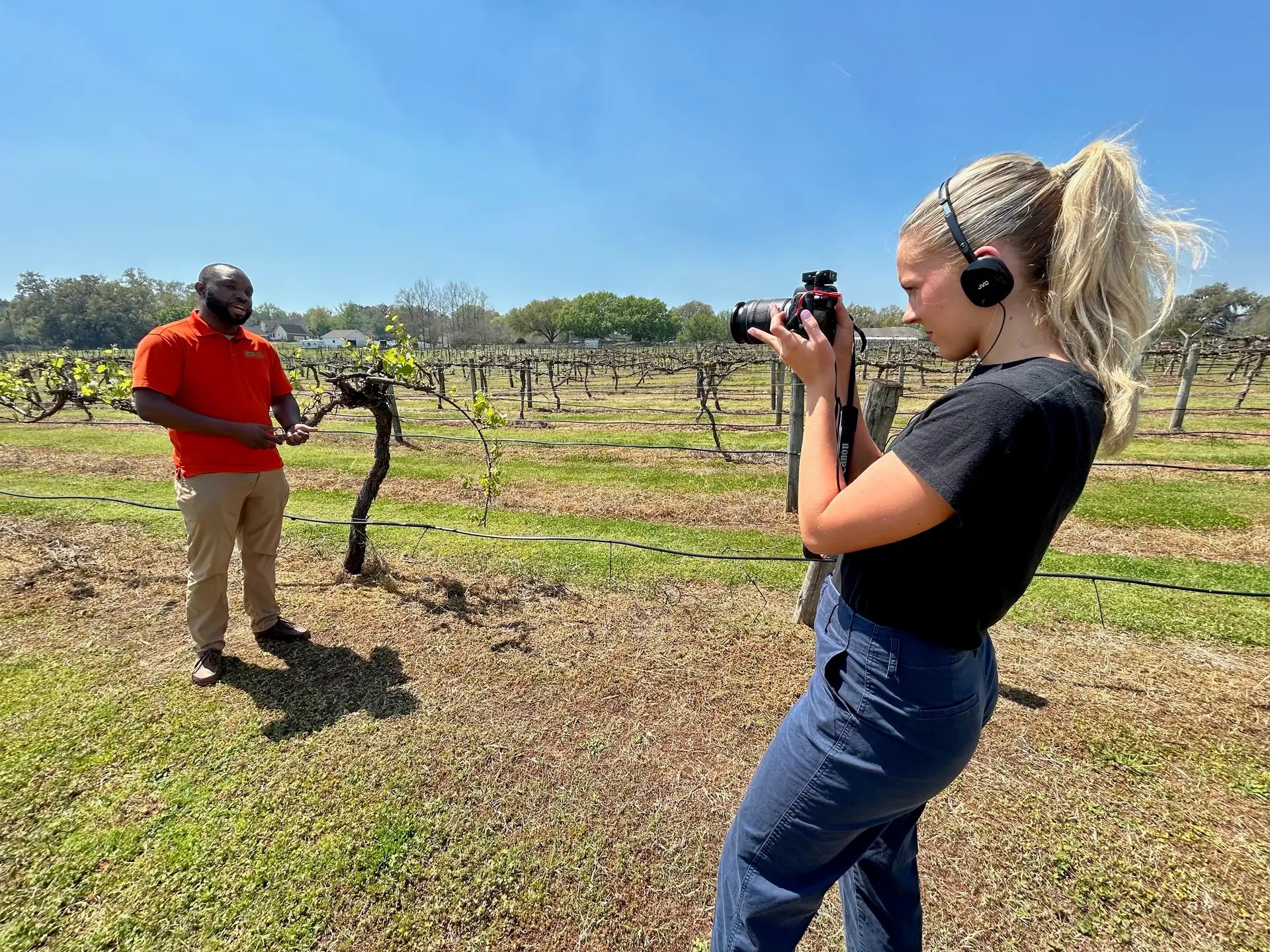 Photo of student filming grape science expert outside at a vineyard in Florida.