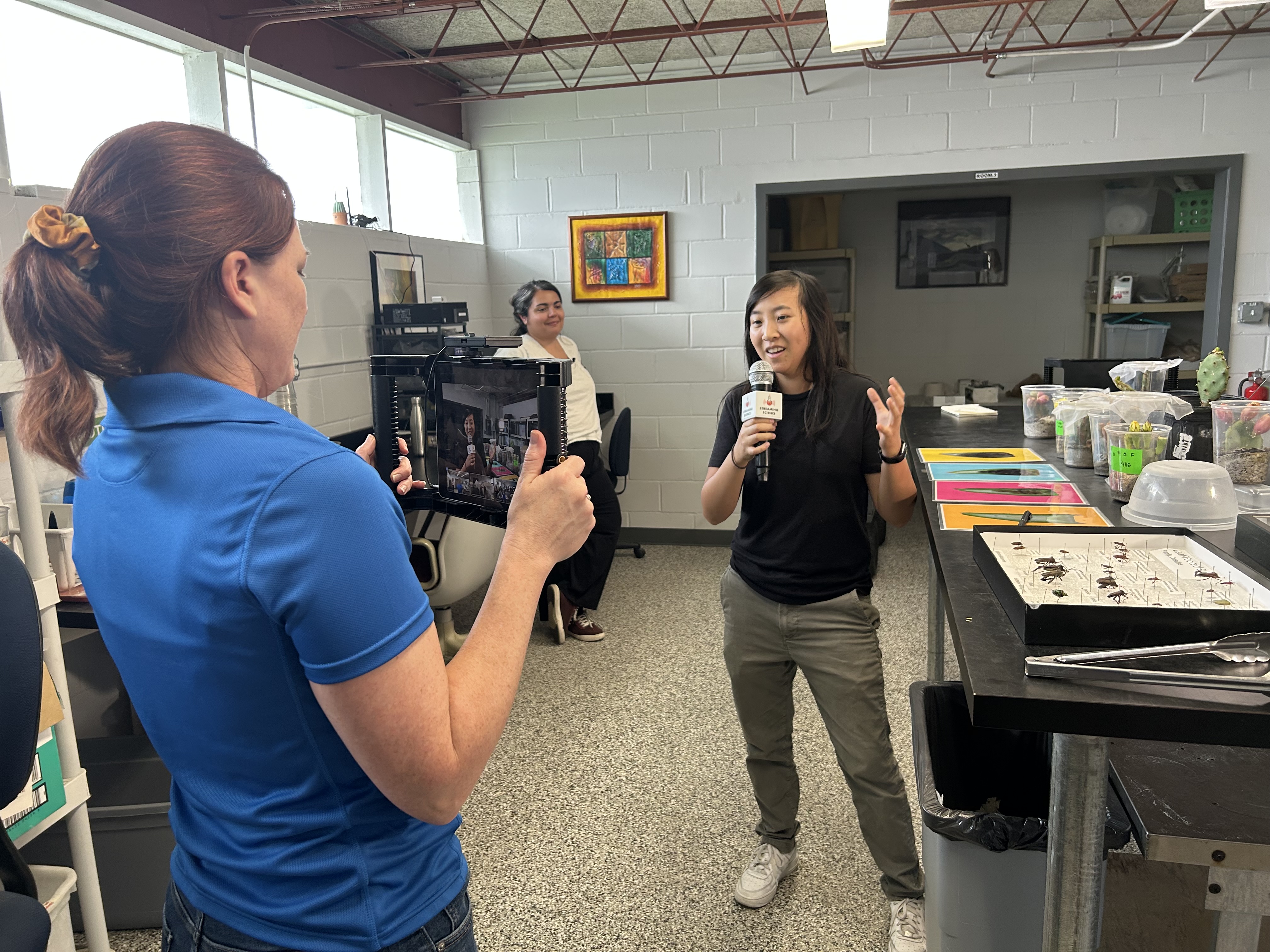 Student holds an iPad to live stream the Bug Battles electronic field trip.