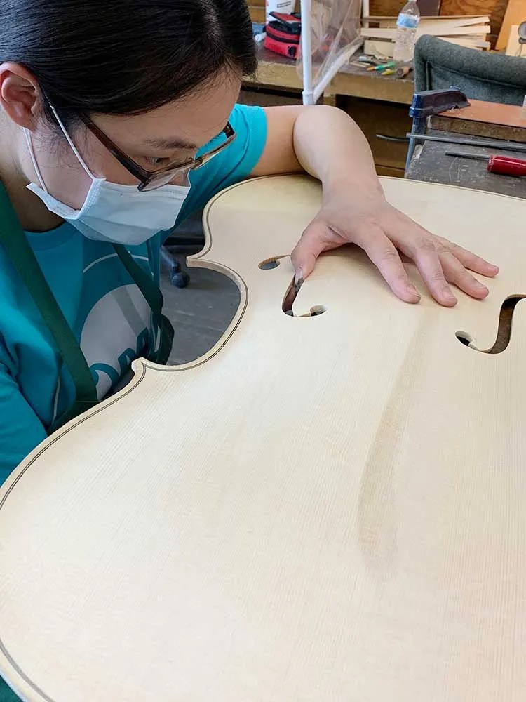 VMSA student Yu En Hsu inspecting a cello top.