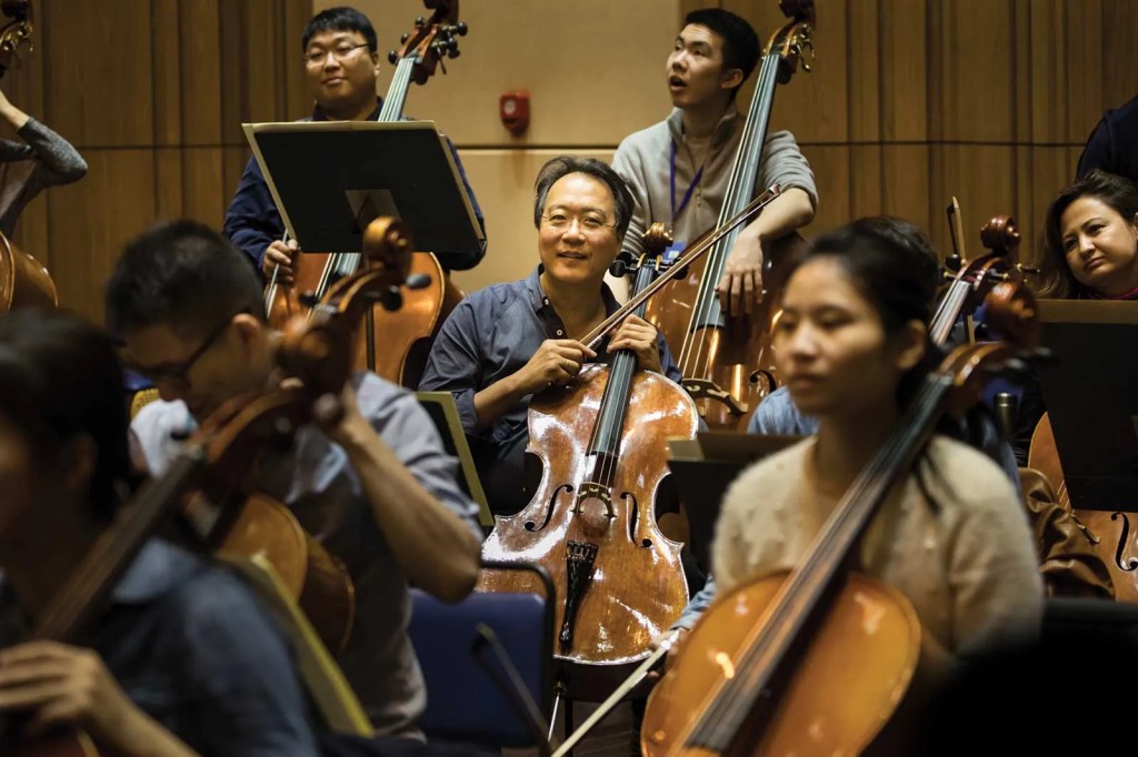 Yo-Yo Ma sits in the back of the cello section during orchestra rehearsal at YMCG.