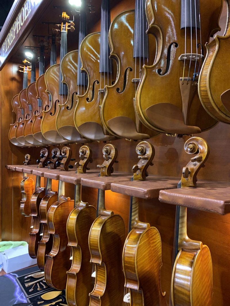 a row of violins hanging on display at Winter NAMM 2019