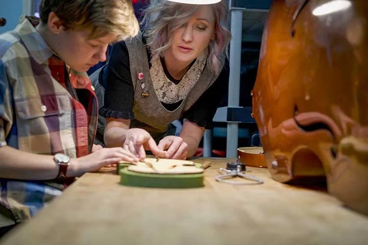Luthier Rozie DeLoach at the workbench working on an instrument