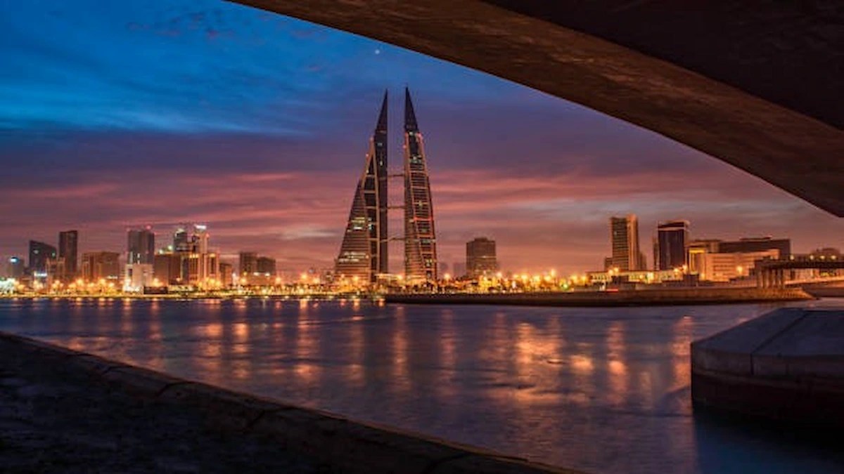 Alt Text: Bahrain skyline featuring the Bahrain World Trade Centre illuminated at dusk, representing the new Bahrain Civil Service Rules.