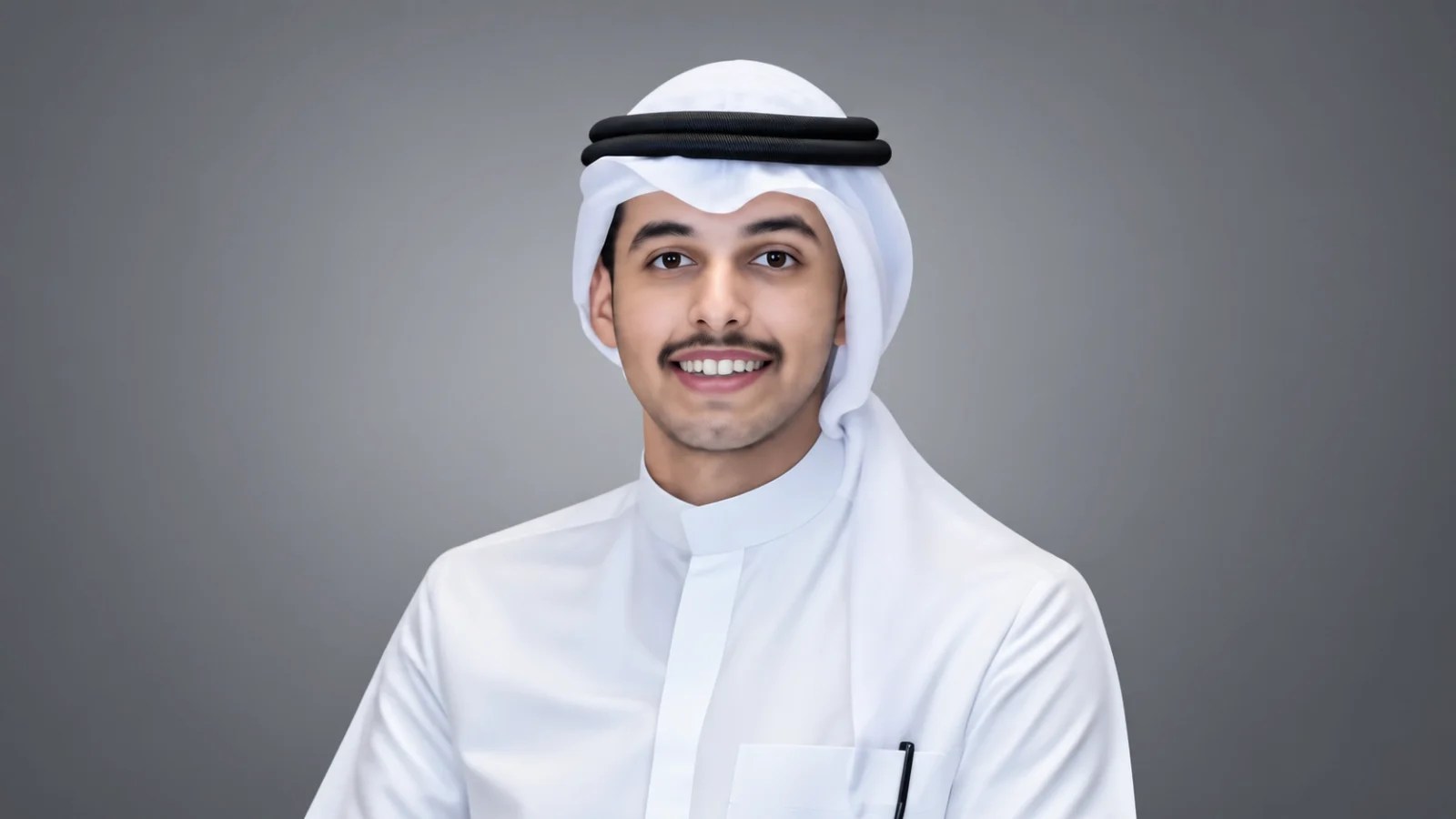 Portrait of Bandar Alafasi wearing traditional Kuwaiti attire, including a white thobe and ghutra, against a grey background.