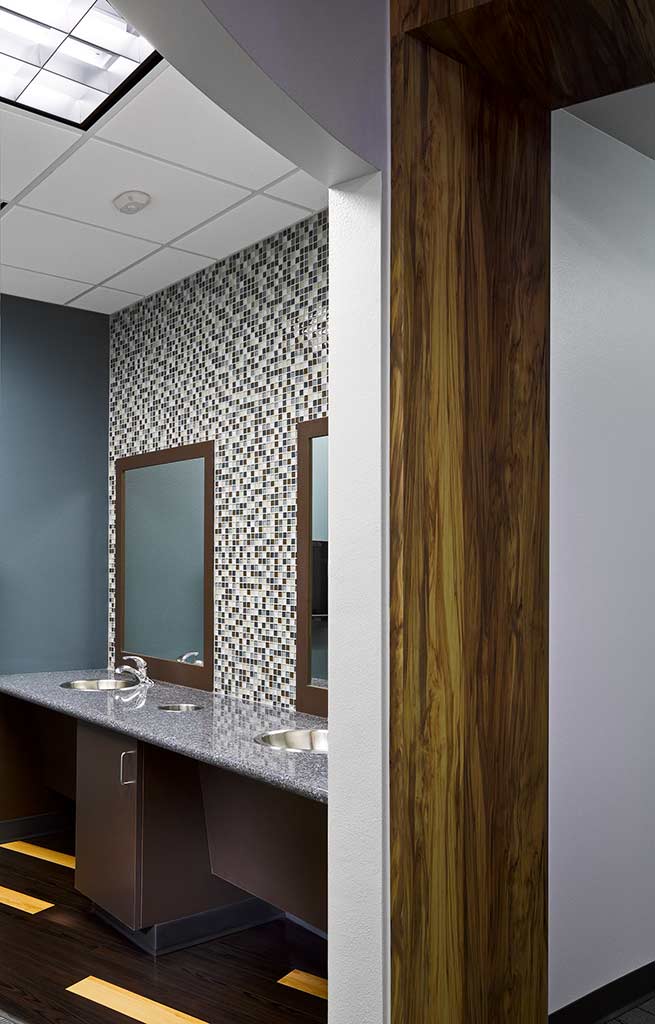 Interior of a modern bathroom with two sinks, mirrors, and decorative tiled wall.