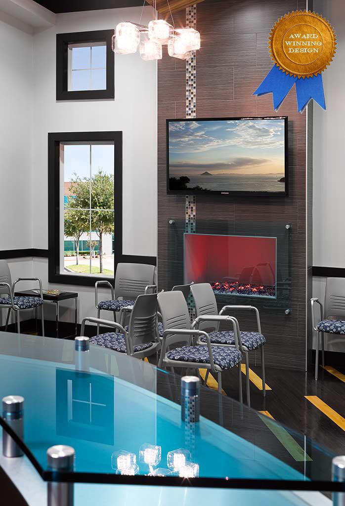 Modern waiting area featuring stylish chairs, a wall-mounted TV displaying a scenic view, and a sleek glass counter. The space is illuminated by a unique chandelier and decorated with a decorative fireplace.