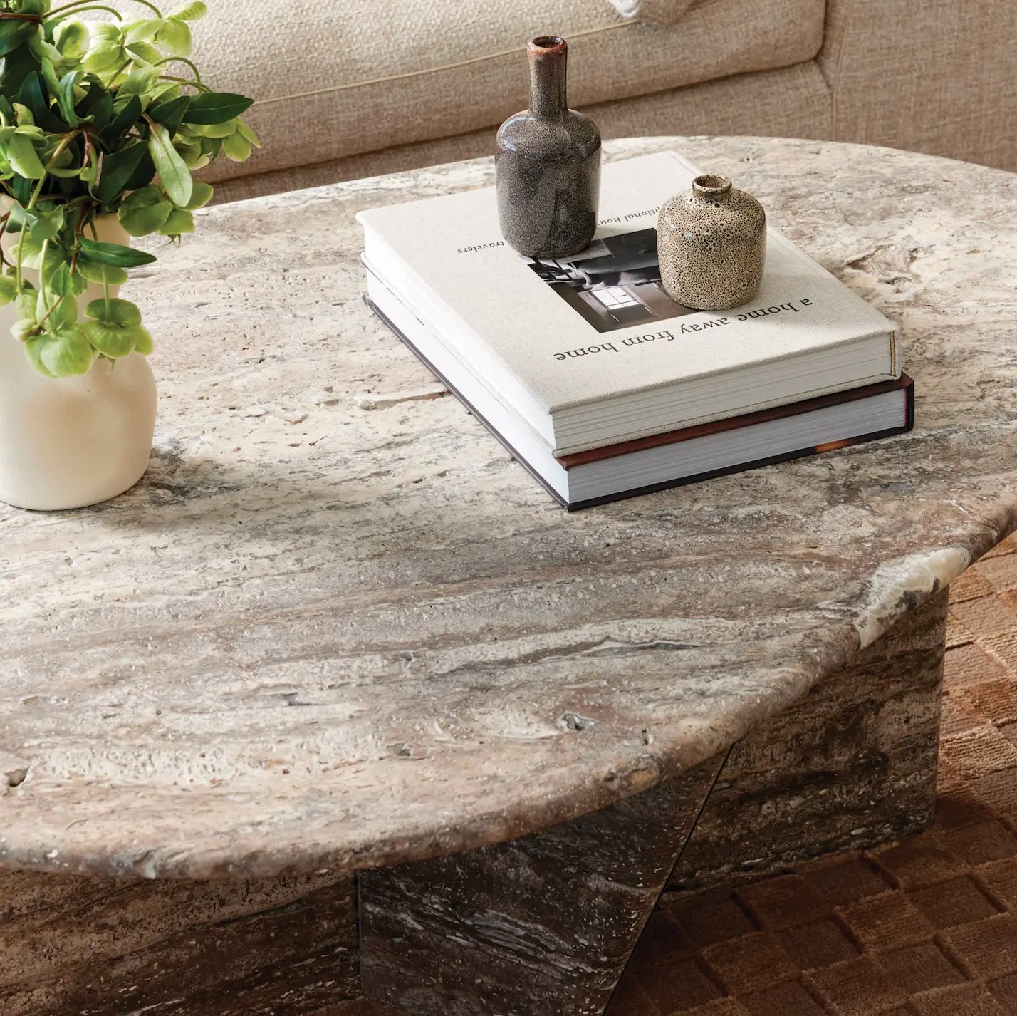 Custom stone coffee table made of silver travertine and minimal styling with books and greenery.