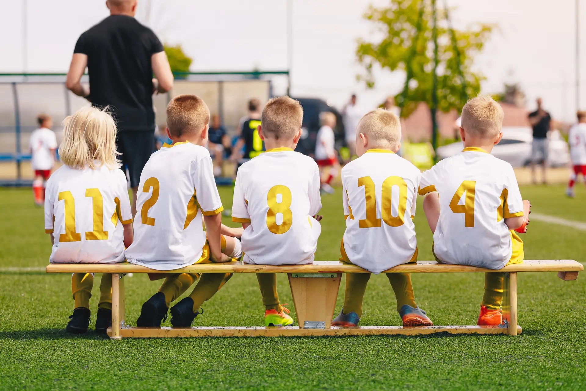 A random image of youth soccer players sitting on a bench watching their team play