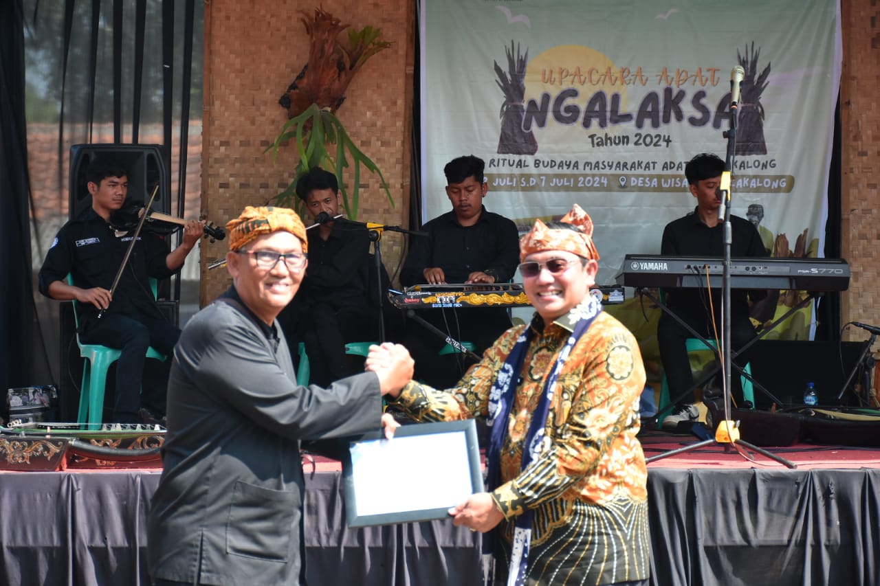 Pj. Bupati Sumedang Yudia Ramli menyerahkan secara simbolis sertifikat penetapan upacara adat Ngalaksa dan Seni Tarawangsa yang ditetapkan sebagai Warisan Budaya Tak Benda (WBTB) oleh Kementerian Pendidikan dan Kebudayaan (Kemendikbud) kepada Camat Rancakalong Cecep Supriatna dan para pelaku seni Tarawangsa dalam acara pembukaan Upacara Adat Ngalaksa di Desa Wisata Rancakalong. Selasa (2/7/2024).