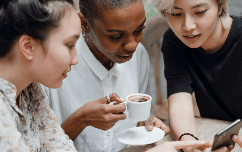Sunset Bridge Consulting helps grow your audience, so that you can connect with new followers and create new client opportunities. Women gathered around a phone talking about a local business they found on social media.