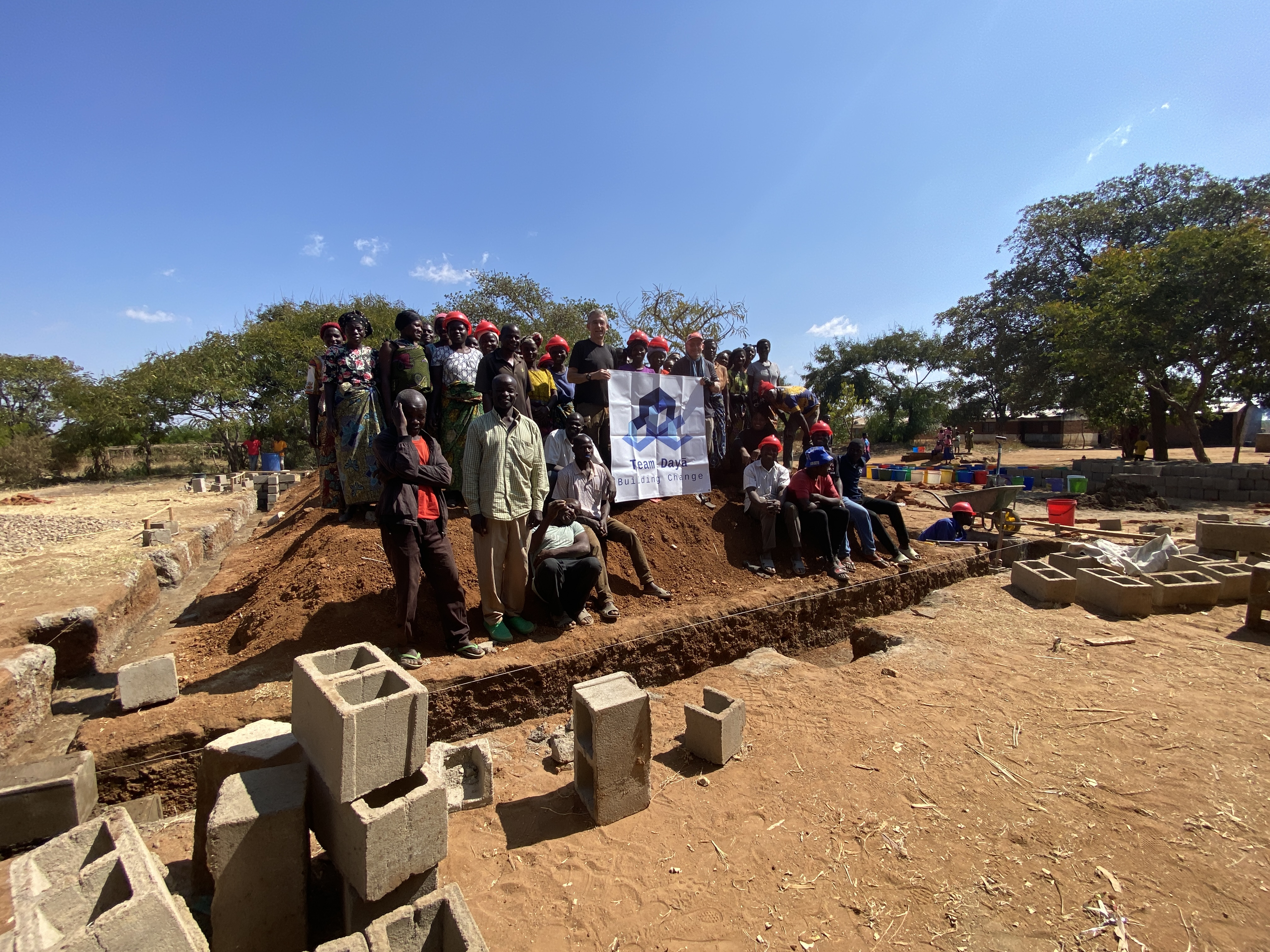 (PHOTO: Team Dayā members Jay Sears and Michael Benedek with community members from Lambwe, Malawi on the school worksite on Thursday, June 26, 2025. It was the 10th project funded by Team Dayā.)