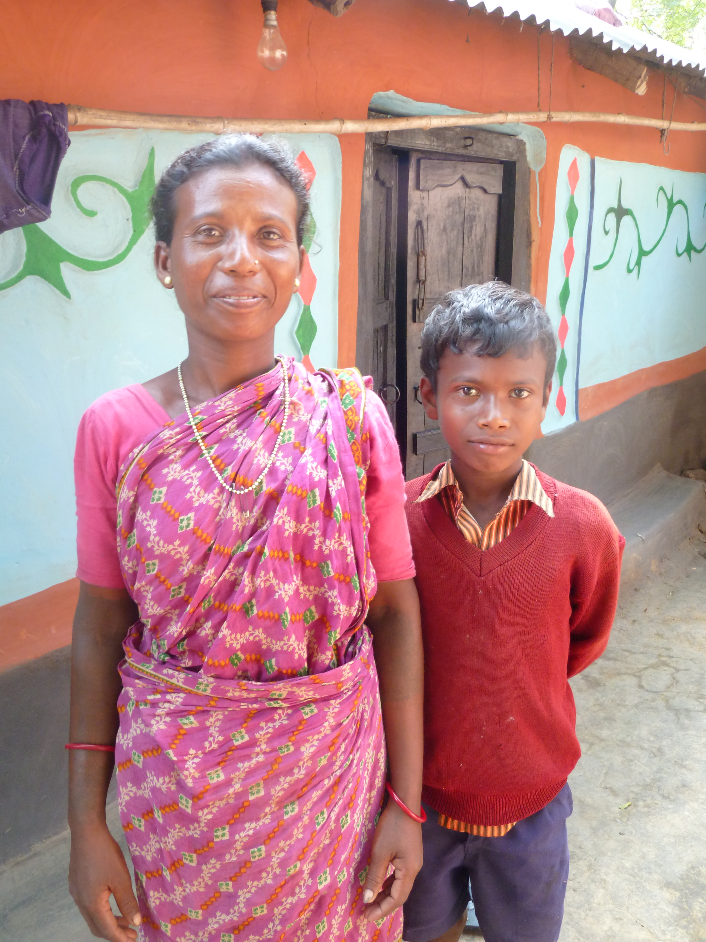 Une femme santale et son fils devant leur maison