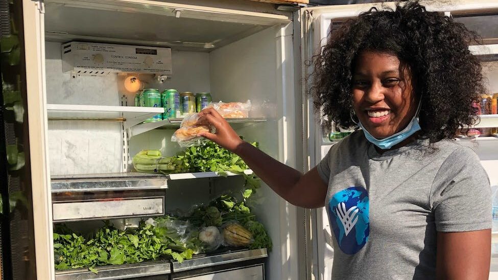 a black female activist looking at camera next to a food bank