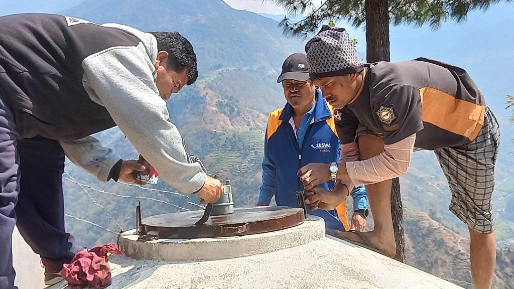 Three men installing a sensor on top of a water tank in Naumule