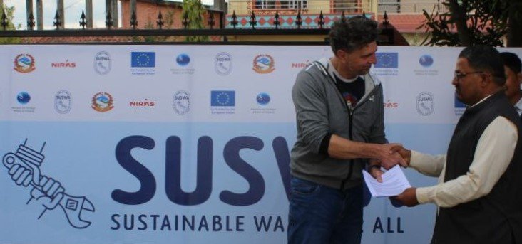 Two men shaking hands outside in front of a SUSWA logo