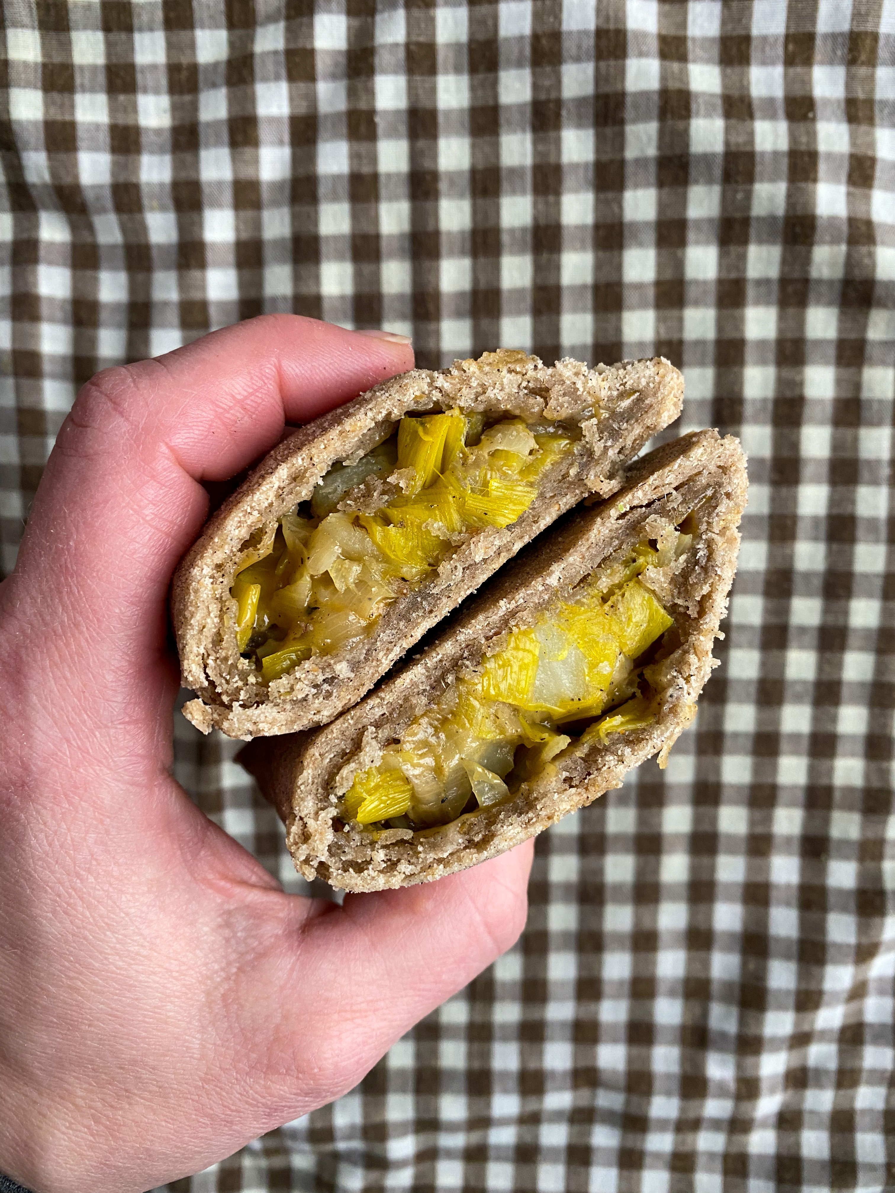 Pasty cut in half and held in hand showing filling