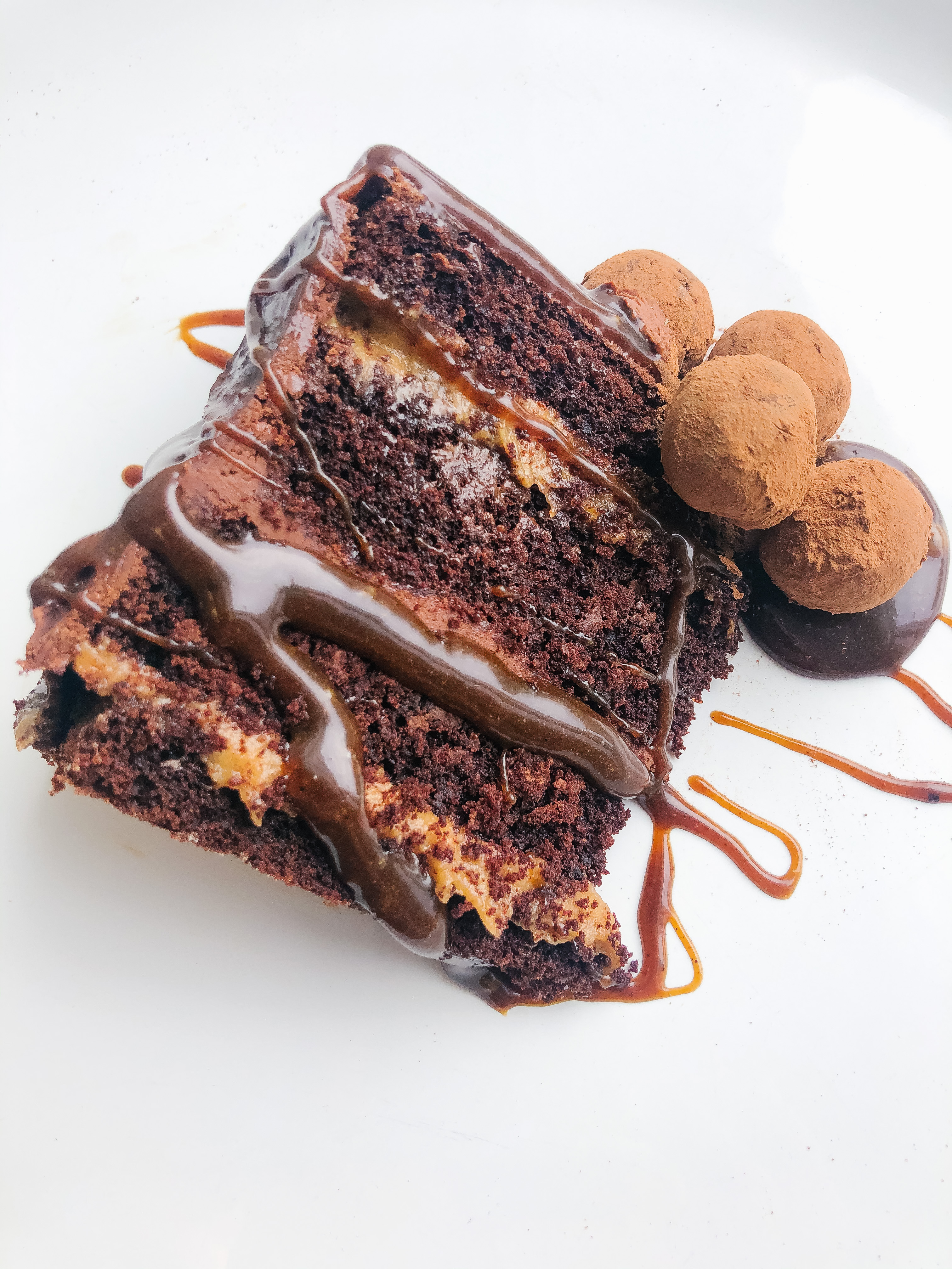 Top view of chocolate cake slice, four layers chocolate frosting, caramel sauce, topped with chocolate truffle