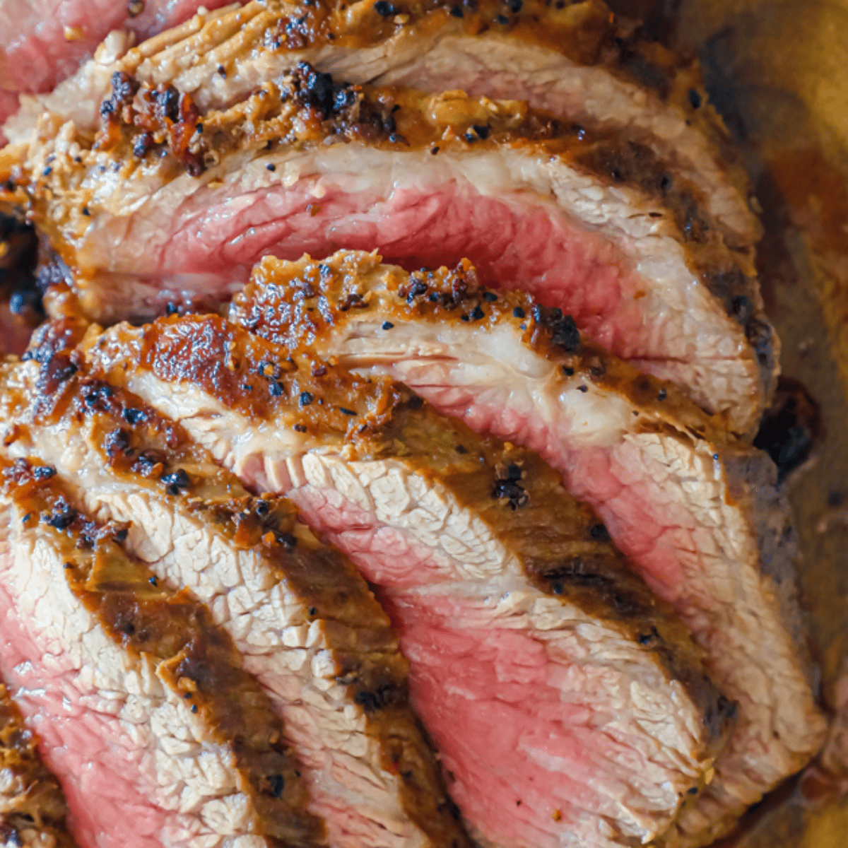 Close-up of several slices of medium-rare roast beef, featuring a browned crust and juicy pink center—perfect inspiration for your next Keto Tri Tip Steak or Best Broiled Tri Tip Steak using your favorite ninja foodi steak recipe.